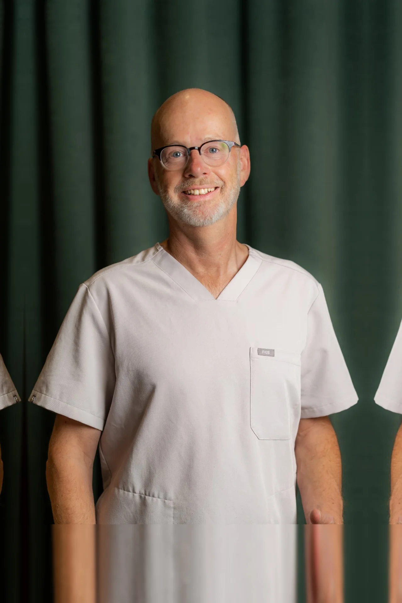 Porträt von med. dent. Thilo Grauheding, Zahnarzt im Zahnärztehaus Zürich in grauer Praxisbekleidung.